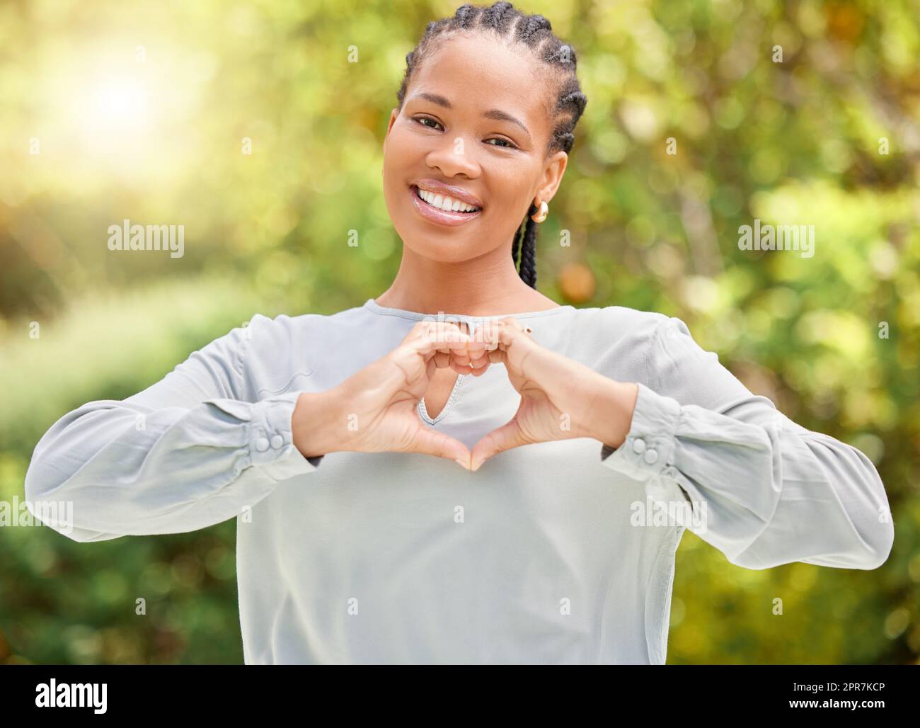 Amo l'aria aperta, una giovane donna che fa un gesto di cuore con le mani in natura. Foto Stock