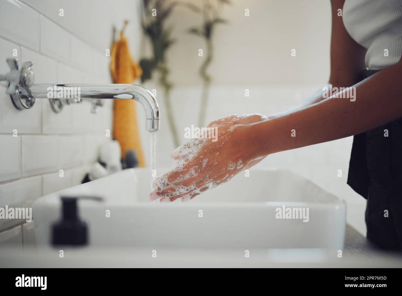 Primo piano delle mani femminili con sapone e lavare le mani con acqua pulita sotto l'acqua corrente. Donna latteria e risciacquo per prevenire la diffusione di germi, infezioni batteriche Foto Stock