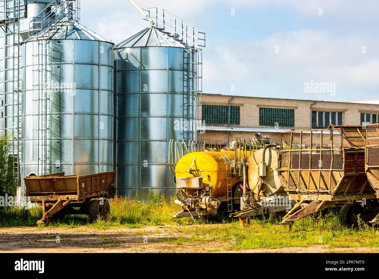 Cantiere agricolo con rimorchi agricoli, serbatoi e stoccaggio del grano Foto Stock