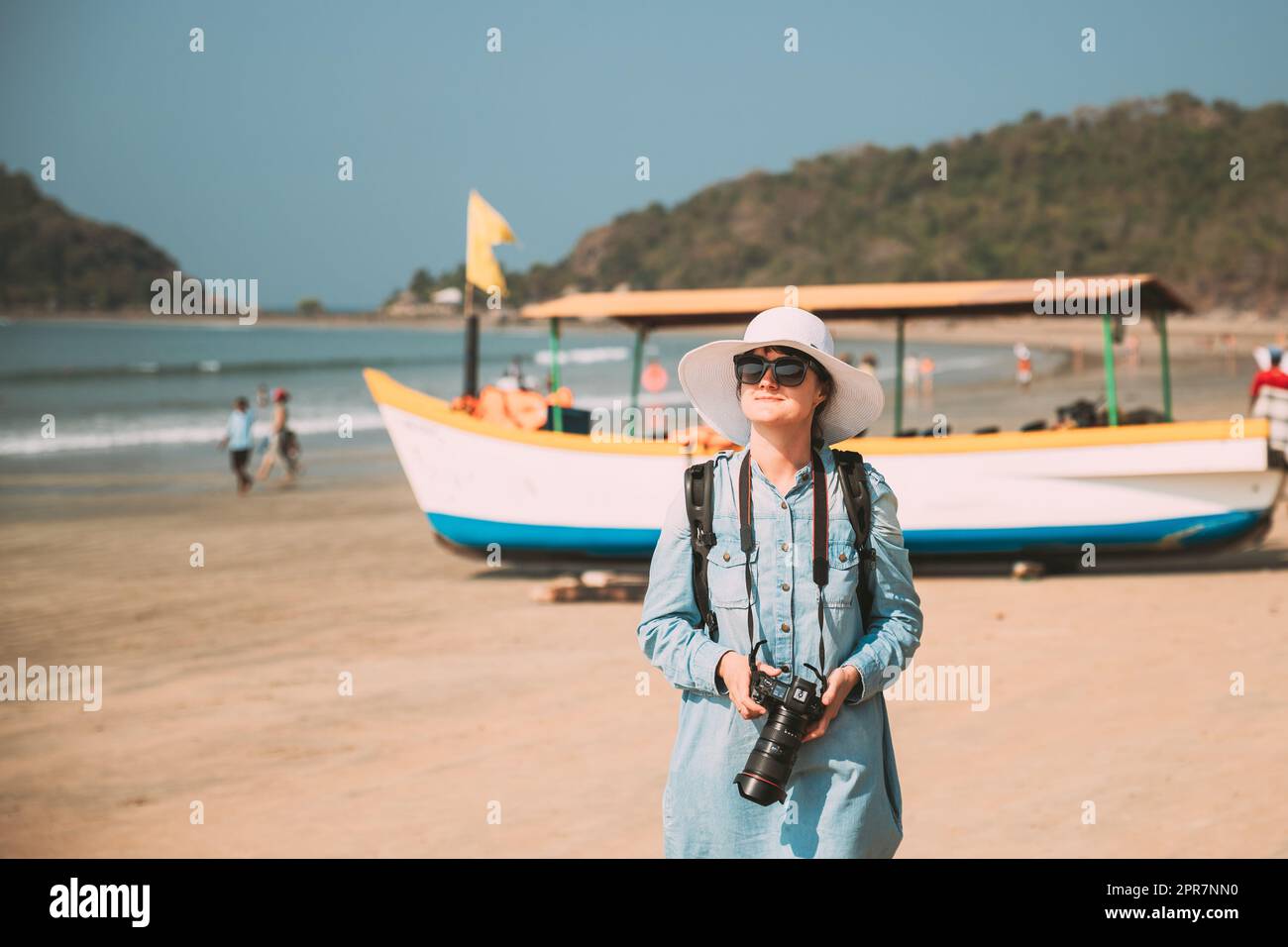 Canacona, Goa, India. Giovane donna caucasica con macchina fotografica in piedi sulla famosa spiaggia di Palolem vicino al Mare Arabico in estate giorno di sole Foto Stock