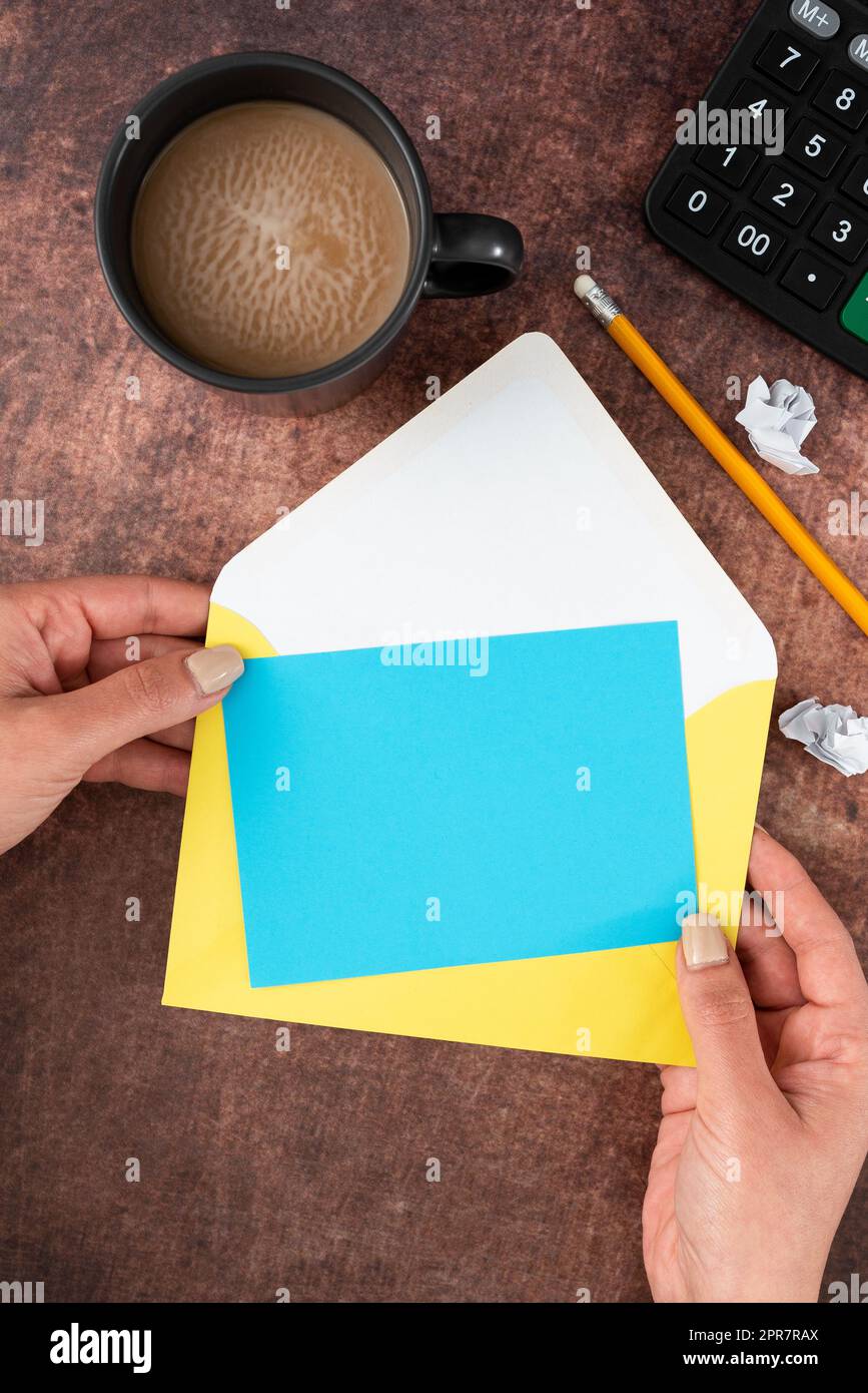 Mani di donna con carta a colori con spazio per la copia, busta, tazza da caffè e cancelleria su sfondo di legno. Donna d'affari che rappresenta un messaggio cruciale e importante. Foto Stock