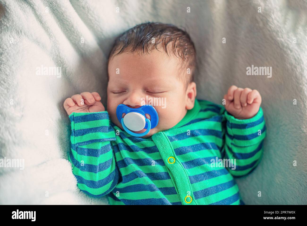 Neonato addormentato con braccia sollevate e succhietto in bocca Foto Stock