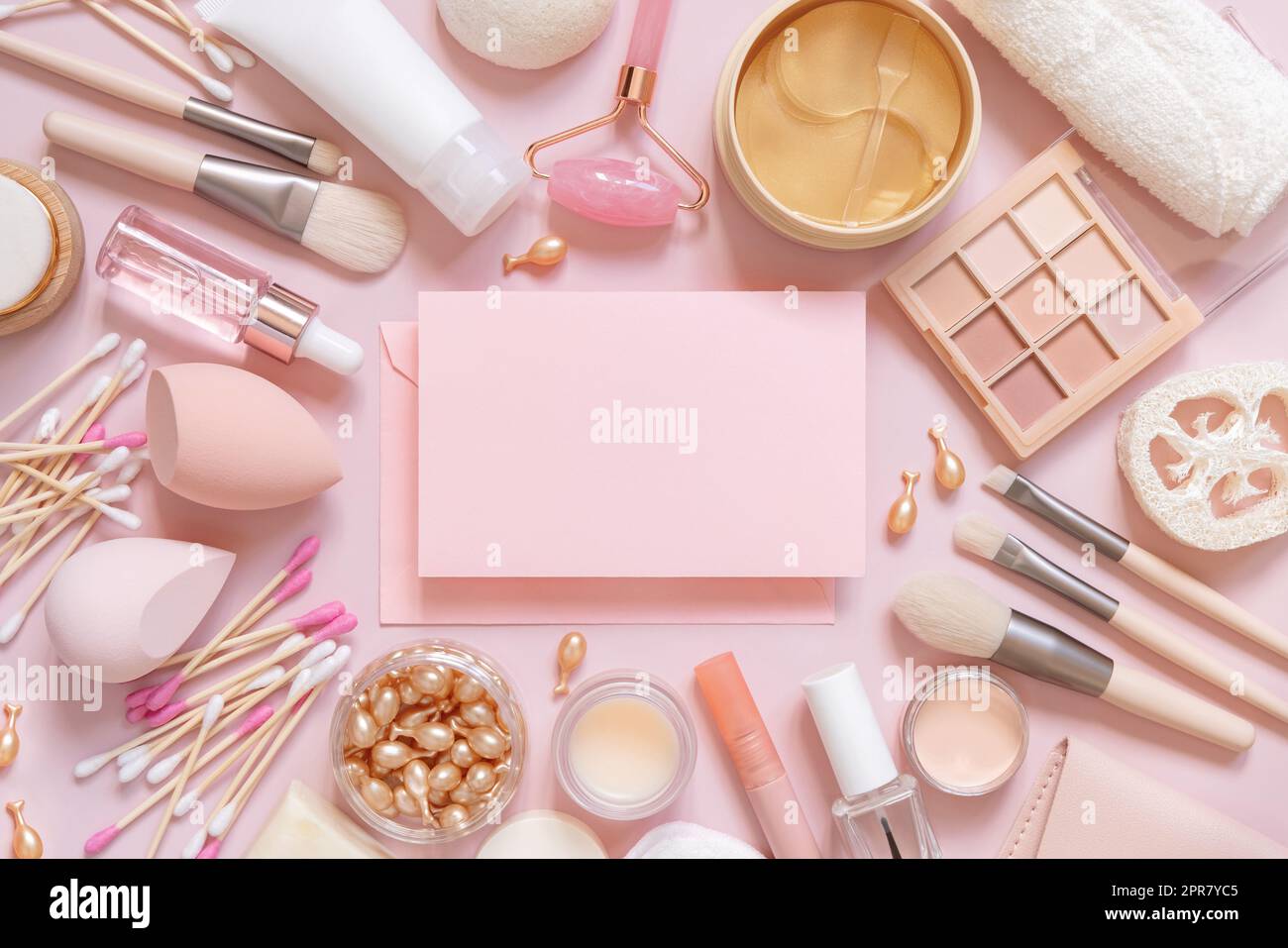 Cartoncino di carta tra la cura della pelle e i cosmetici decorativi su rosa, vista dall'alto, mockup Foto Stock