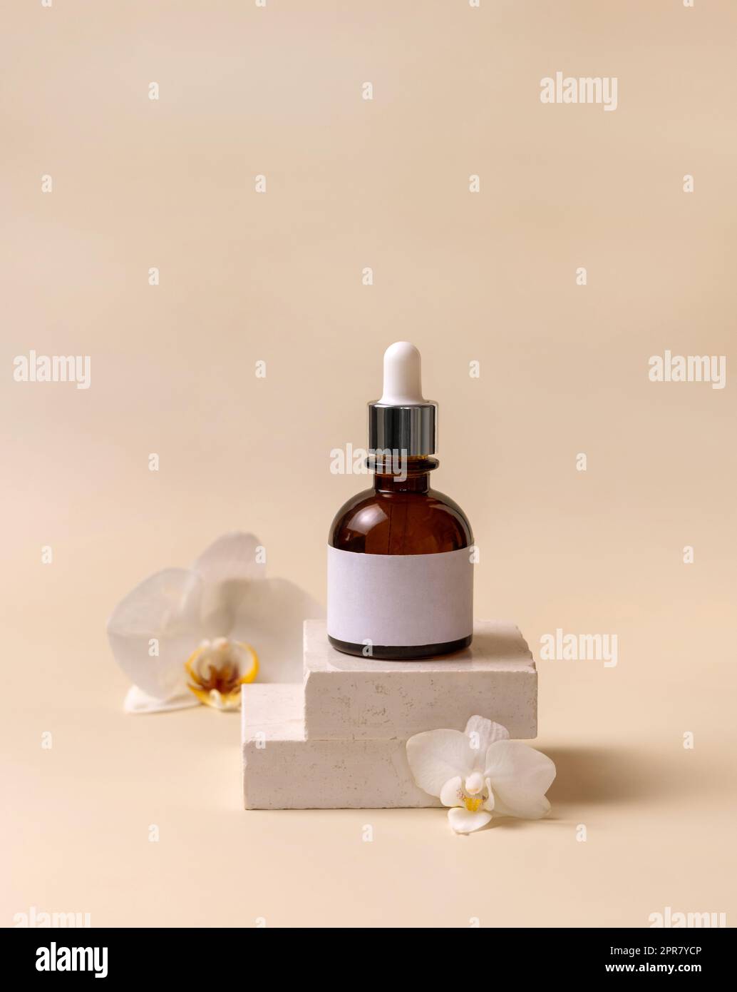 Bottiglia di vetro contagocce su pietra vicino a fiori di orchidea bianchi di colore giallo chiaro, Mockup cosmetico Foto Stock
