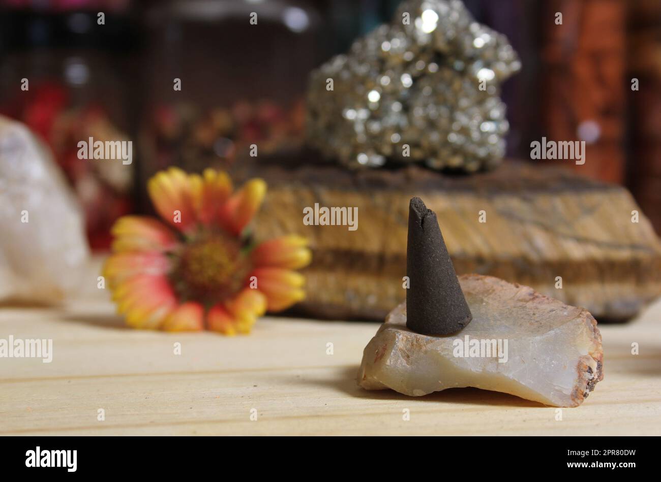 Cono di incenso su pietra con cristalli e fiori Foto Stock