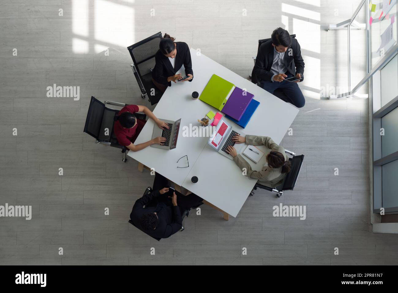 I dirigenti aziendali lavorano sullo stesso tavolo in un ufficio moderno con computer portatile, tablet, telefono cellulare e caffè. Concetto di team aziendale People. Vista dall'alto Foto Stock