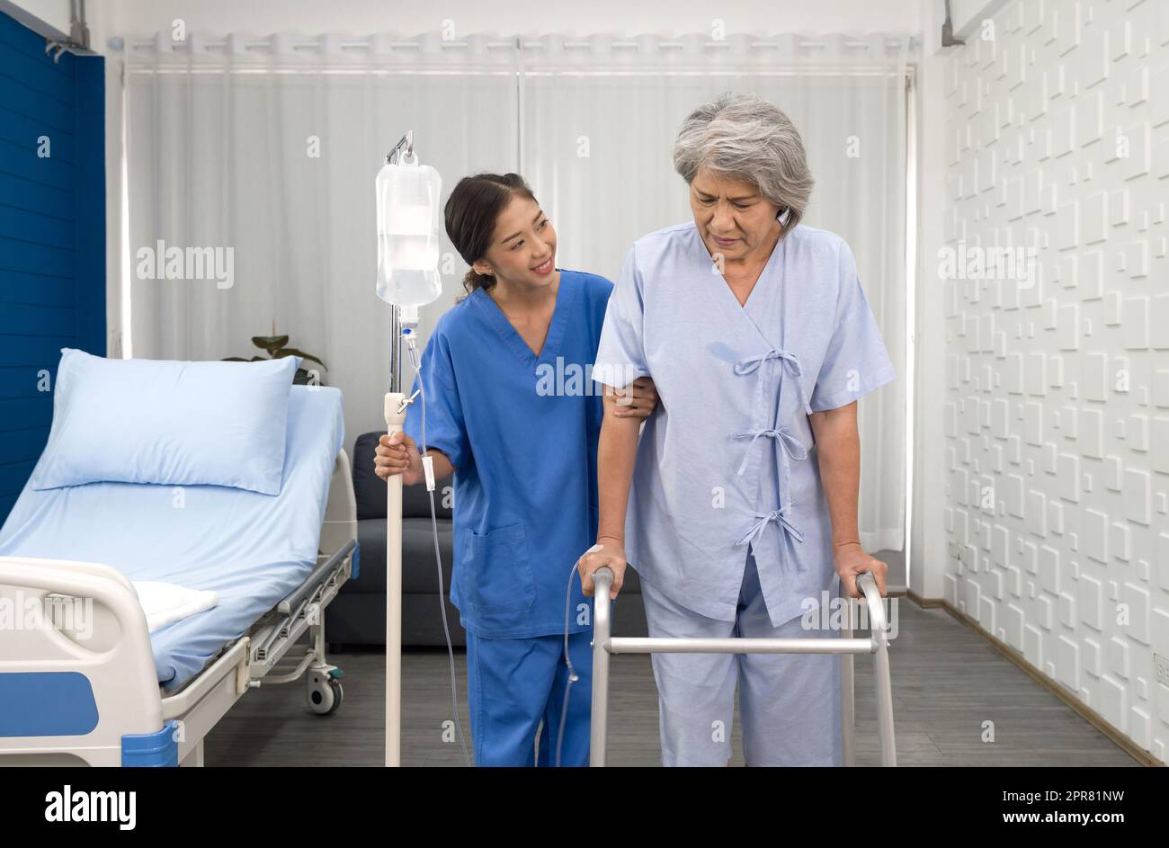 Giovane infermiera asiatica a casa di cura cura anziani disabili donna. Il medico curante serve la fisioterapia per i pazienti anziani per esercitarsi e praticare la camminata sul camminatore o sulla canna da zucchero. Foto Stock