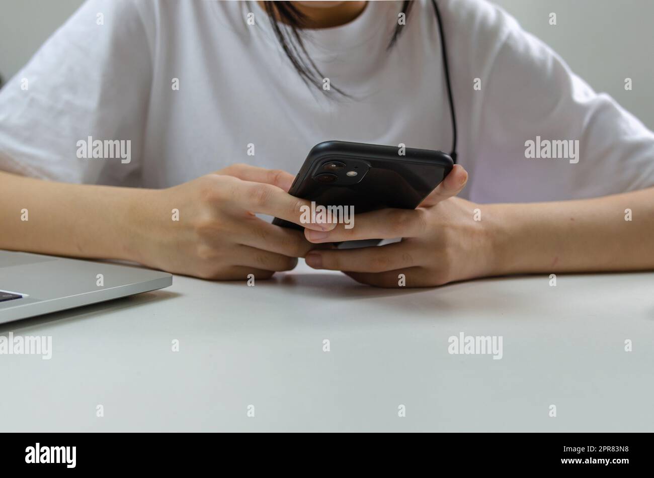 Giovane ragazza che tiene la comunicazione mobile dello smartphone e la tecnologia digitale di rete sociale del Internet sul tavolo. Foto Stock