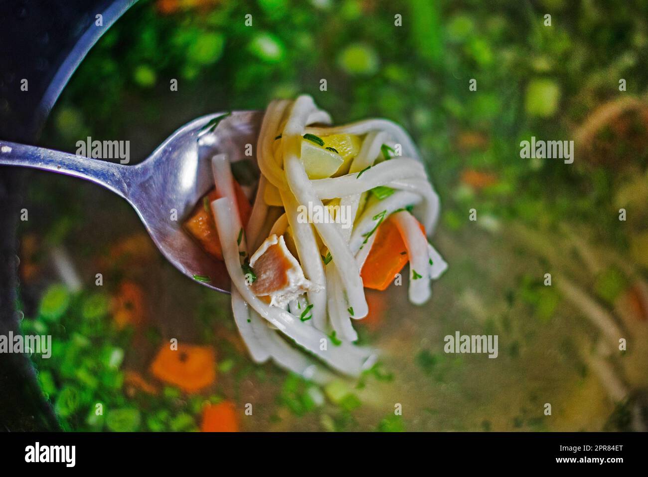 cucchiaio completo con pasta di carote e pezzetti di pollo sullo sfondo della zuppa di verdure. cuoci a casa Foto Stock