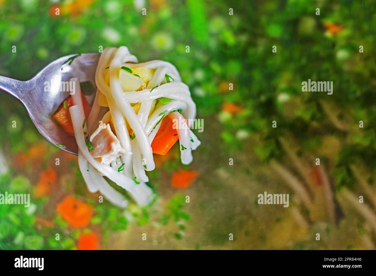 cucchiaio completo con pasta di carote e pezzetti di pollo sullo sfondo della zuppa di verdure. cuoci a casa Foto Stock