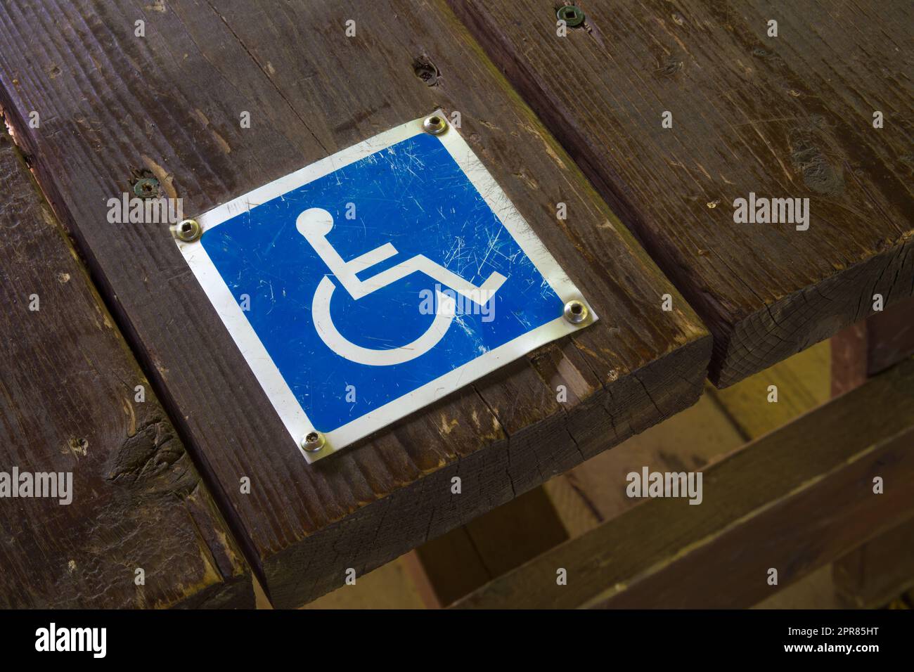 cartello handicap accessibilità sedia a rotelle pittogramma blu metallo su legno Foto Stock