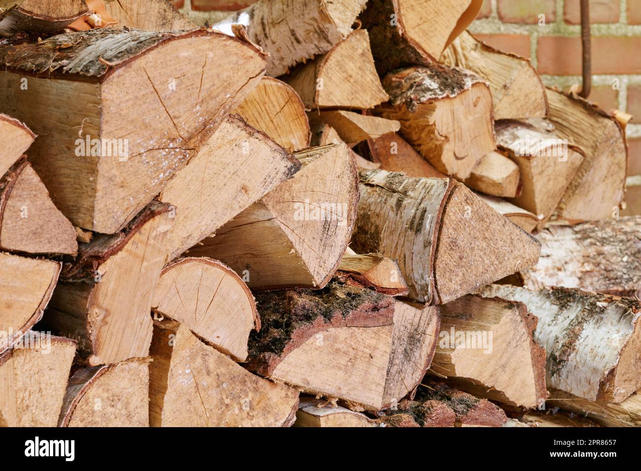 Vista della legna da ardere tagliata e dei tronchi impilati insieme in un cumulo di stoccaggio con spazio di copiatura. Primo piano dello sfondo e della trama in legno. Raccolta di legno duro rustico secco come fonte di energia o per mantenere caldo Foto Stock