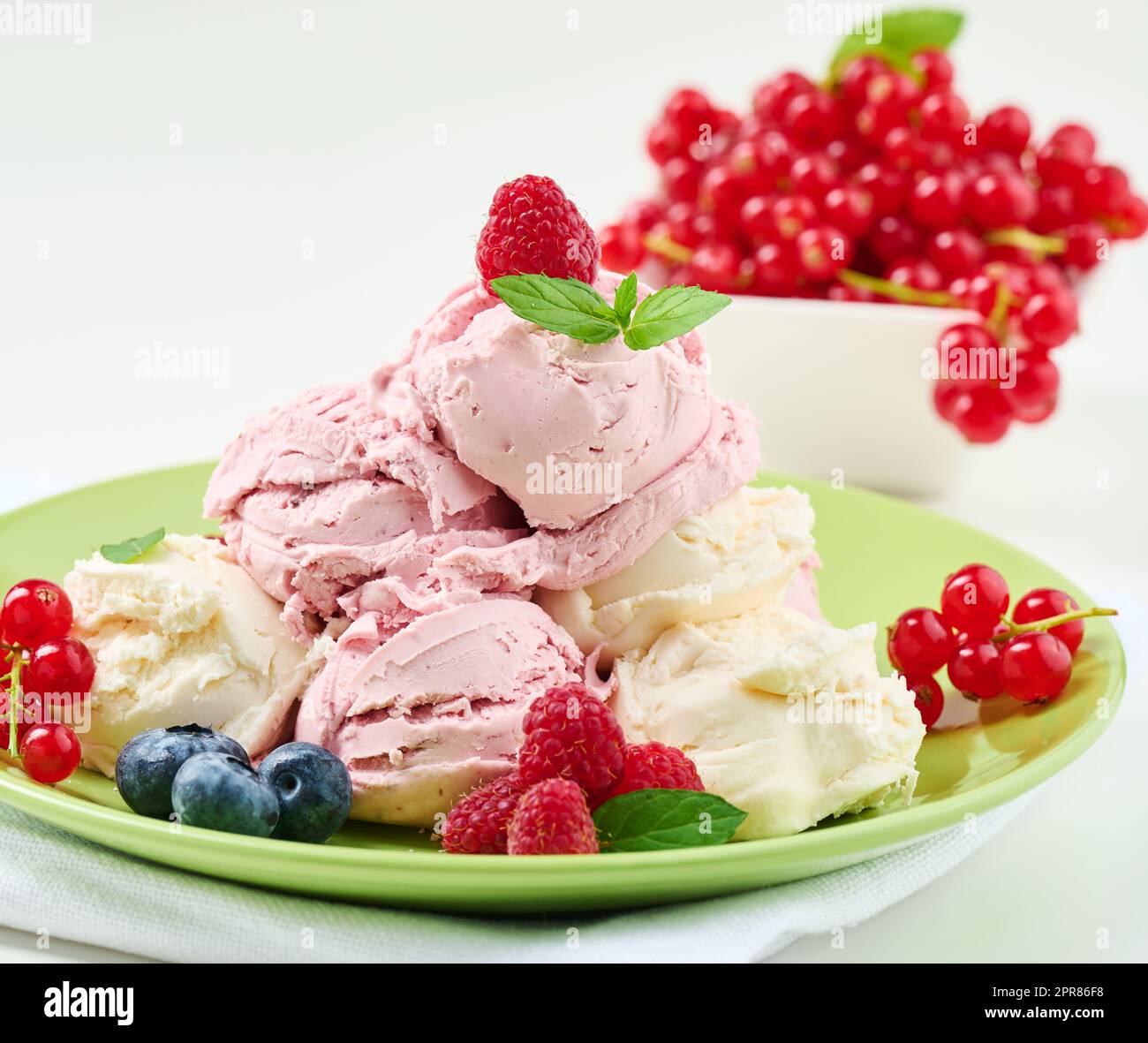 Misurini per gelato alla vaniglia e al lampone su un piatto rotondo verde Foto Stock