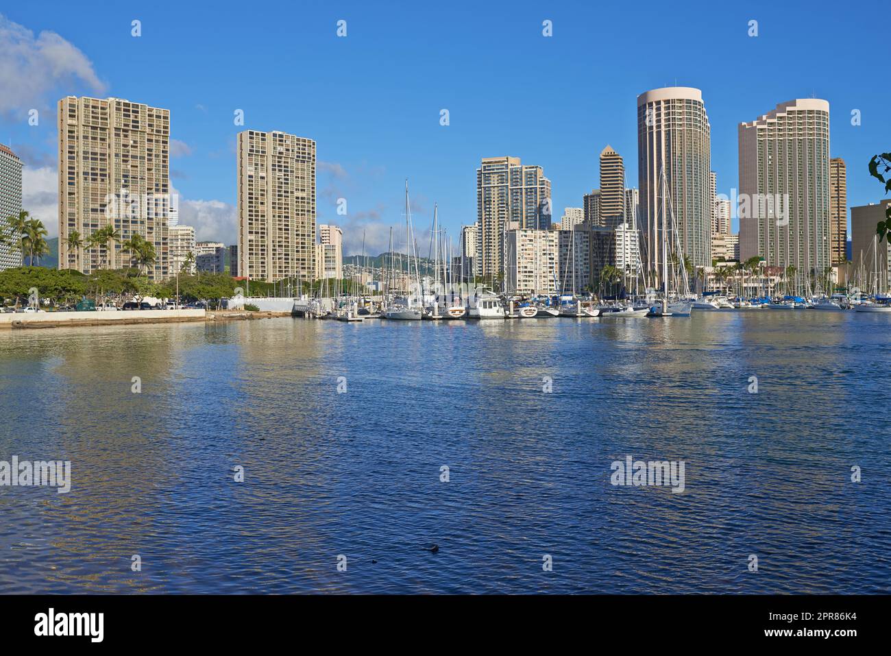 Appartamenti o quartieri degli affari accanto al porto in una giornata di sole con un cielo blu nuvoloso. Una popolare località turistica per le vacanze estive alle Hawaii. Resort di lusso sull'oceano negli Stati Uniti su un mare tropicale Foto Stock