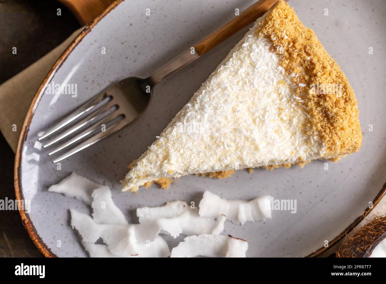 pezzo di cheesecake al cocco su un piatto con cocco fresco Foto Stock