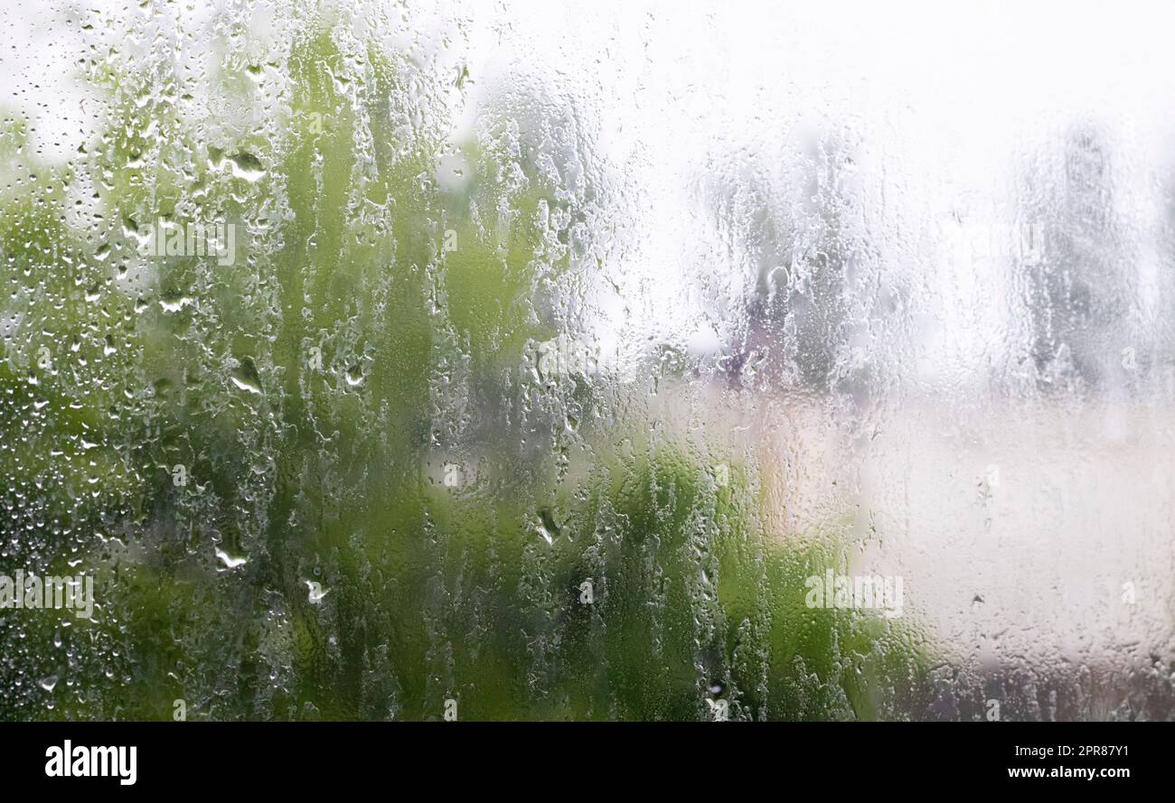 Pioggia intensa. Gocce di pioggia sul vetro della finestra in un giorno d'estate. Messa a fuoco selettiva, bassa profondità di campo. Gocce d'acqua cadono su un finestrino bagnato. Un bicchiere pieno di gocce durante una discesa. Foto Stock