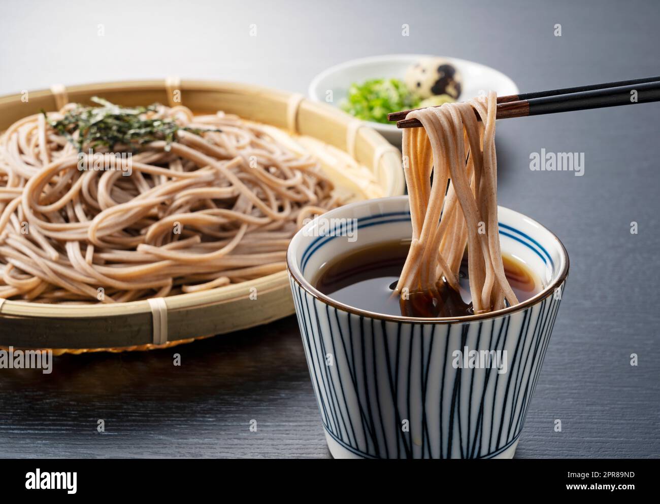 Zaru-soba su sfondo nero. Spaghetti di soba immersi nella zuppa di spaghetti. Foto Stock