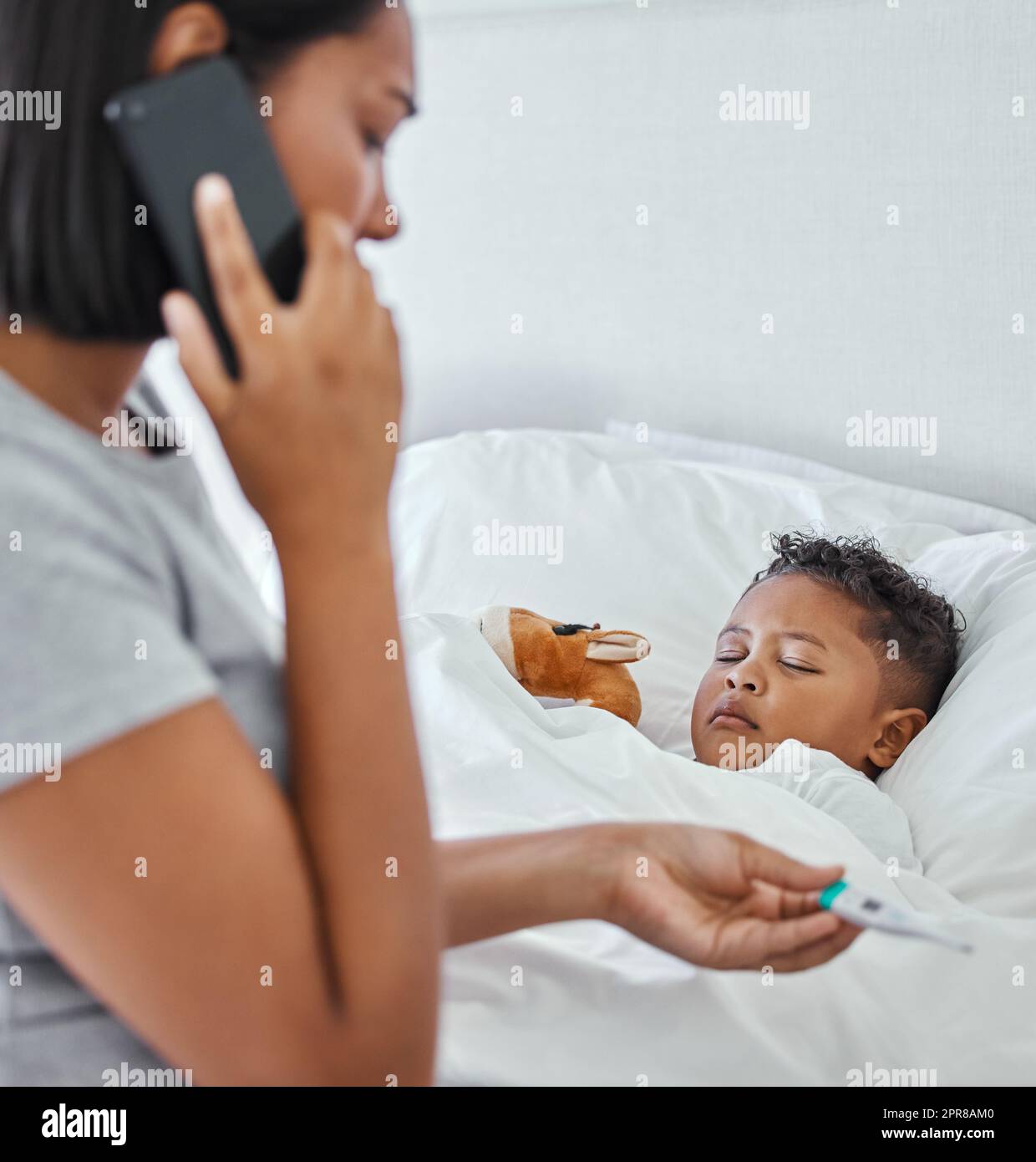 .. Shot di una donna che prende la temperatura dei suoi ragazzi con un termometro a letto a casa. Foto Stock