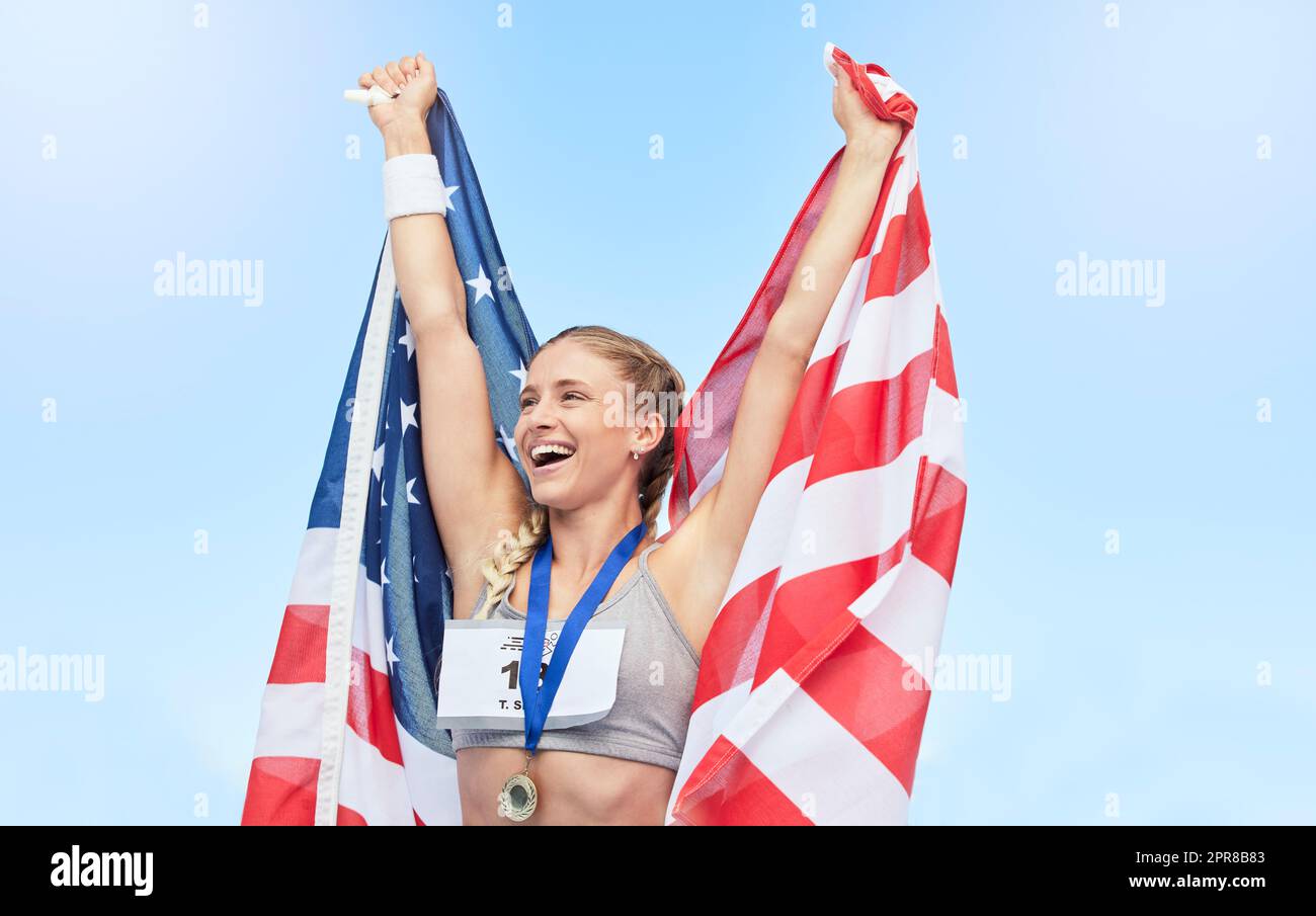 Giovane atleta in forma tifa e tiene bandiera americana dopo aver gareggiato in sport. Una donna sportiva attiva che si sente motivata e festeggia la medaglia d'oro nello sport olimpico Foto Stock