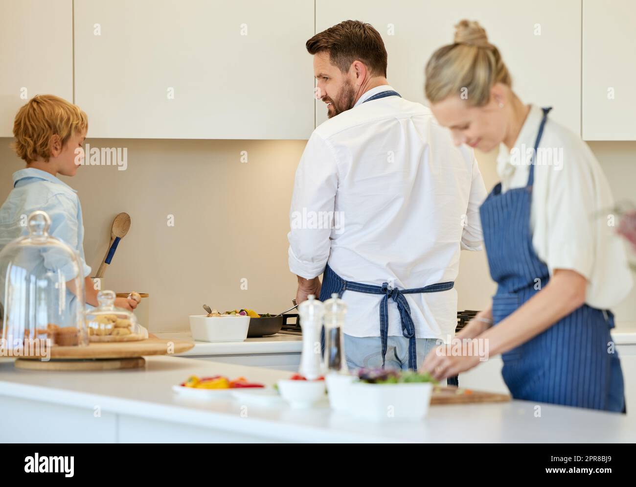 Che cosa volete aiutare con. Una giovane famiglia che cucinano insieme a casa. Foto Stock