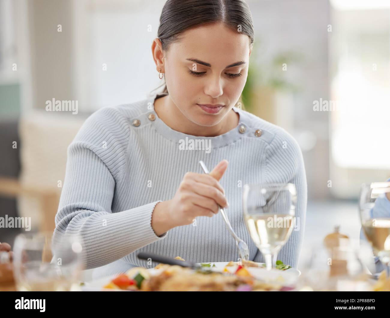 Nessuno cuoca come la mamma. Una giovane donna che si diverse a mangiare con la sua famiglia a casa. Foto Stock