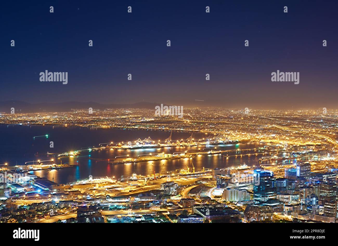 Vista aerea del paesaggio urbano notturno di città del Capo, Sud Africa. Ampio angolo di splendida vista panoramica delle luci della città di sera. Vista ad alto angolo dalla collina segnaletica al buio di una città costiera. Foto Stock