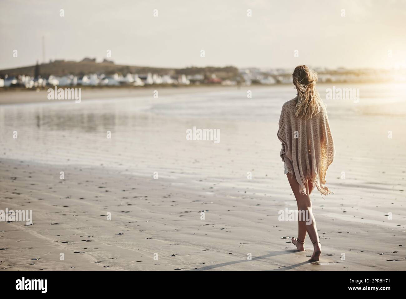 Vicino al mare è dove la sua più calma. Ripresa retrostensiva di una giovane donna che cammina lungo la riva del mare. Foto Stock
