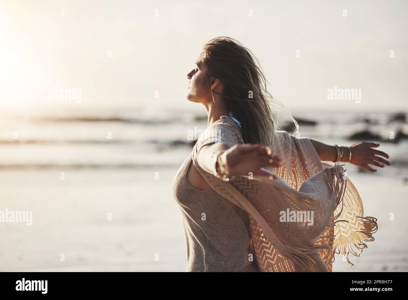 Vivete la vita sul lato soleggiato, una giovane donna attraente in piedi con le braccia distese sulla spiaggia. Foto Stock