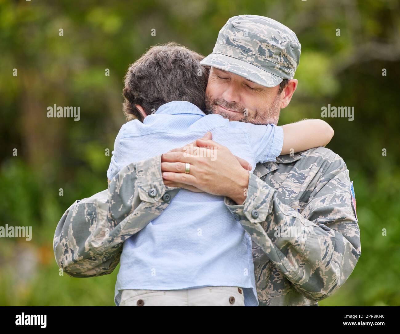 Il legame tra un genitore e un bambino è inscindibile: Un padre che ritorna dall'esercito abbraccia il figlio fuori. Foto Stock
