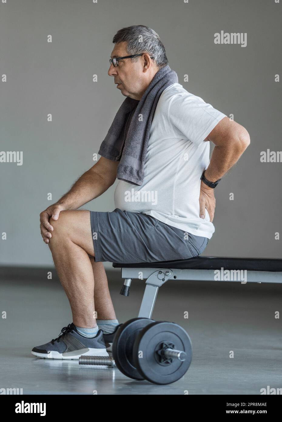 Anziano attivo in palestra con mal di schiena Foto Stock