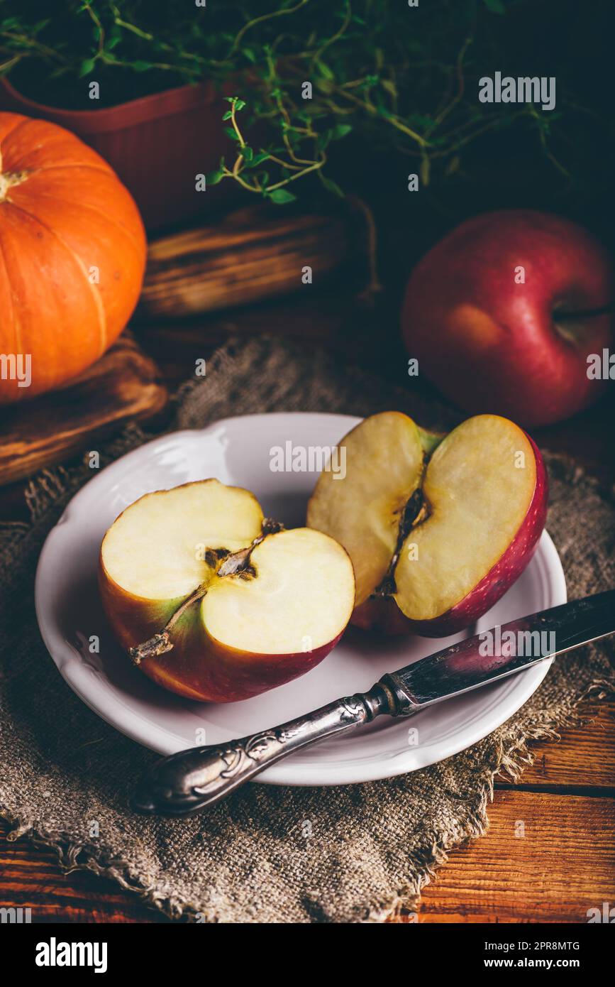 Due metà di mela rossa su piatto bianco Foto Stock
