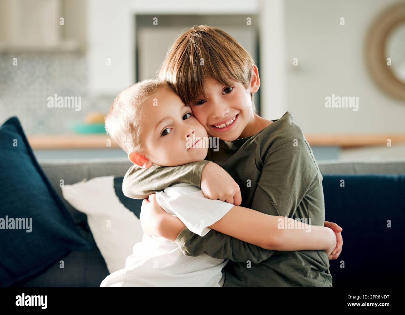 Un grande fratello significa che youre protetto, due piccoli fratelli che si abbraccia sul divano a casa. Foto Stock
