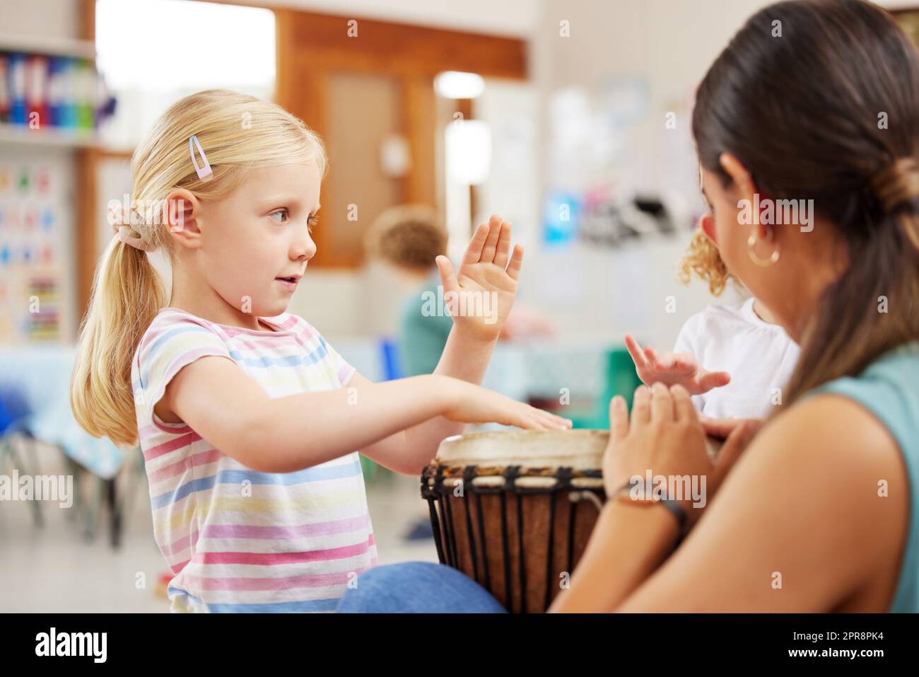La musica è un modo meraviglioso per i bambini di esprimersi: Una donna che insegna a un bambino gli strumenti musicali in classe. Foto Stock