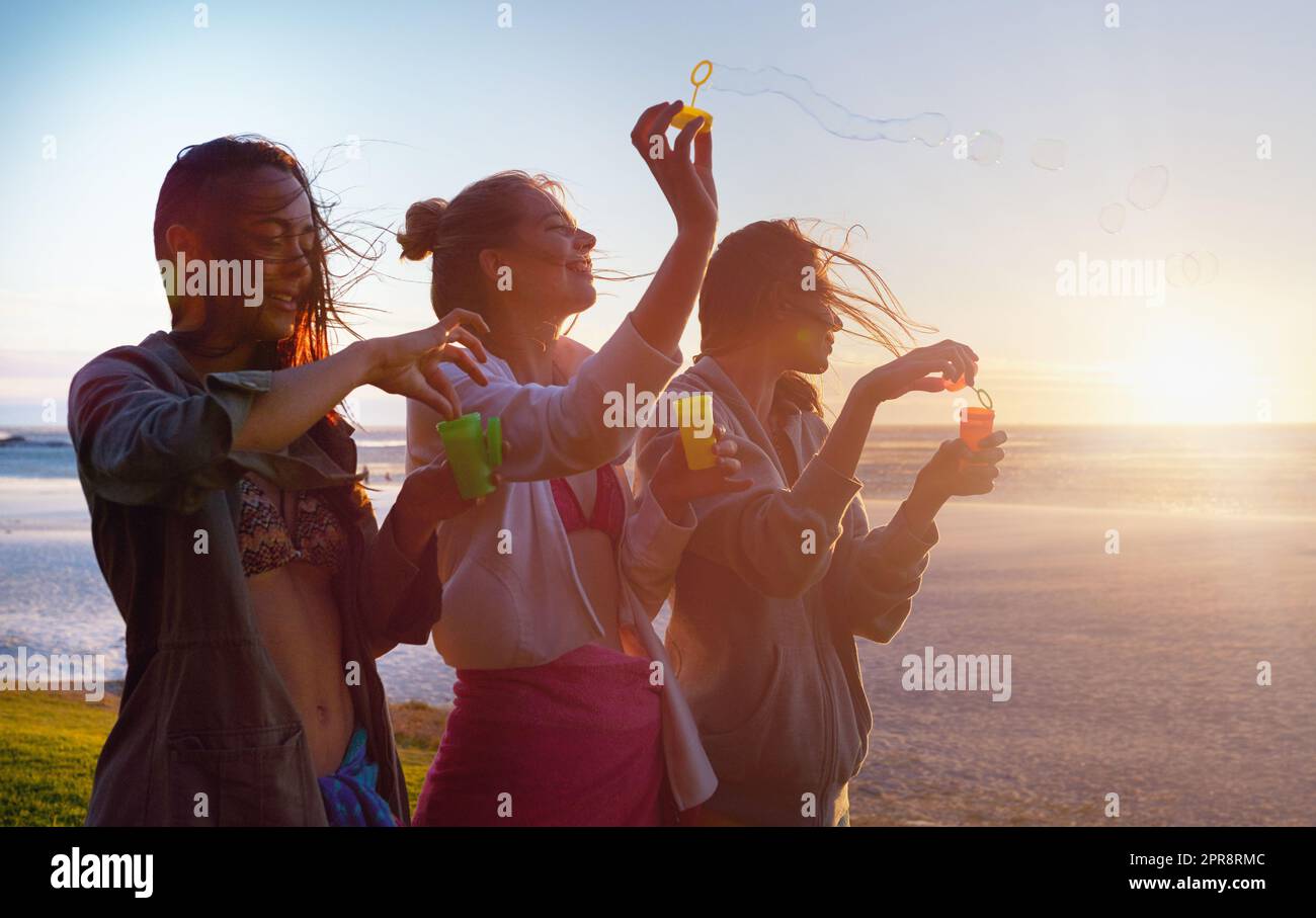 usando la maestà della natura. un gruppo di amici femminili che usano la brezza per soffiare le bolle. Foto Stock