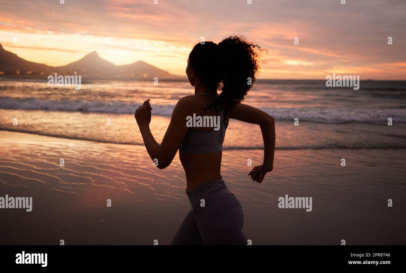 Muovi il tuo corpo. Una donna fuori per una corsa sulla spiaggia al tramonto. Foto Stock
