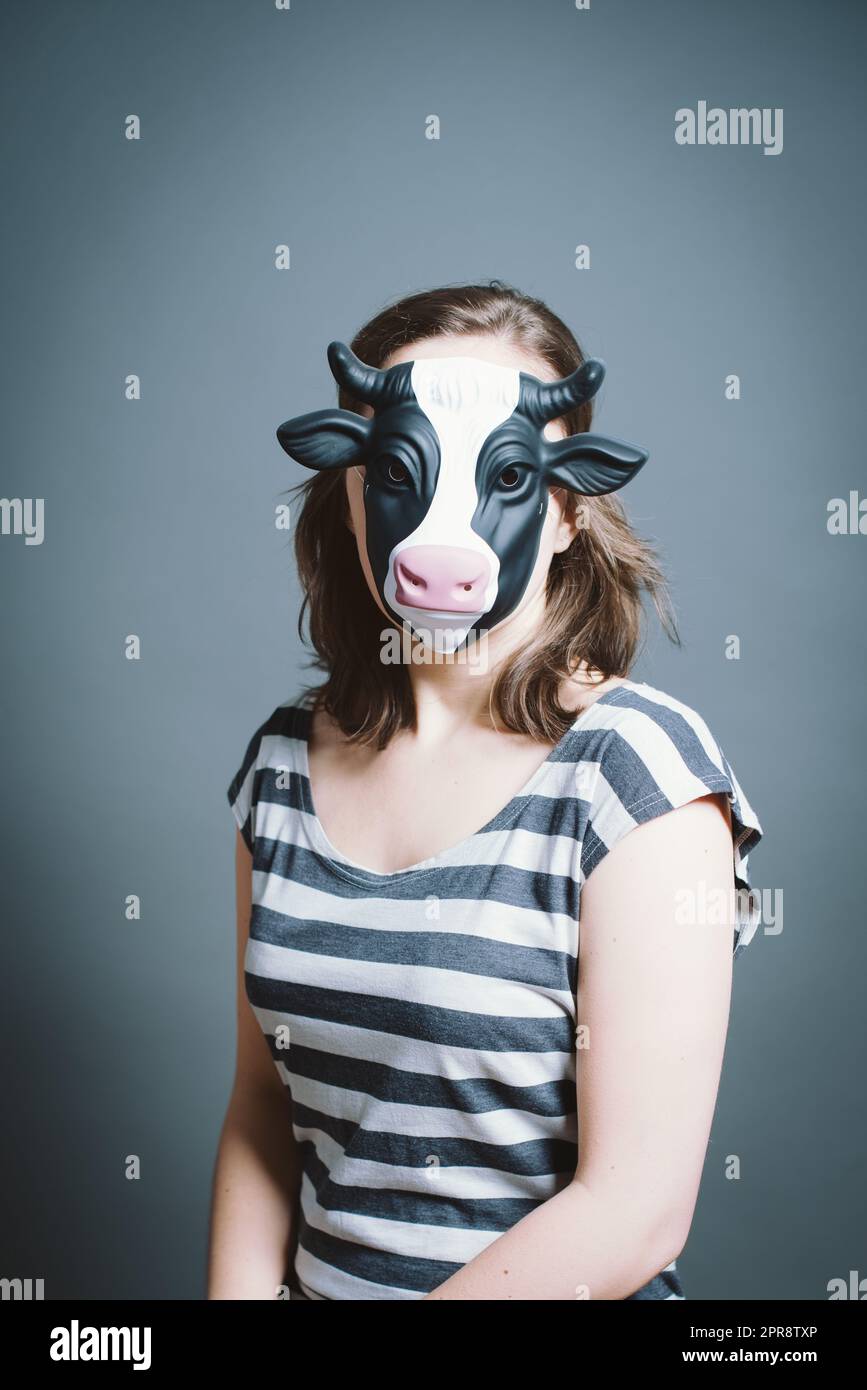 Giovane donna che indossa la maschera su sfondo grigio in studio Foto Stock