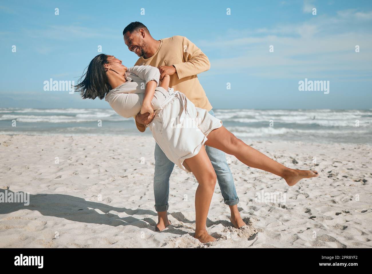 Amando giovane coppia mista gara ballare sulla spiaggia. Felice giovane uomo e donna innamorati godendo momento romantico durante la luna di miele al mare Foto Stock