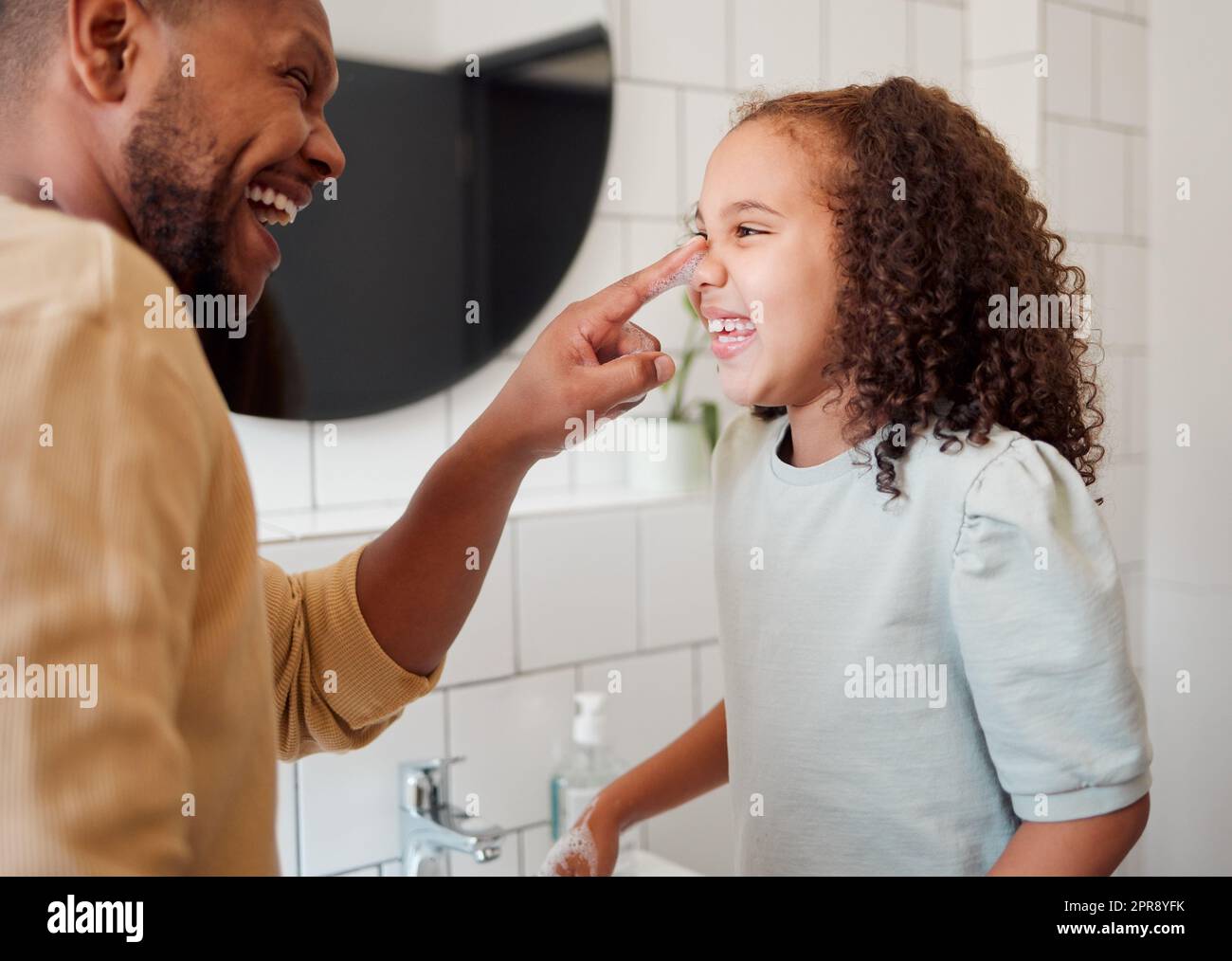 Buon padre e figlia di razza mista che si lavano le mani insieme in un bagno a casa. Un genitore afroamericano single insegnava a sua figlia l'igiene, divertendosi e divertendosi Foto Stock