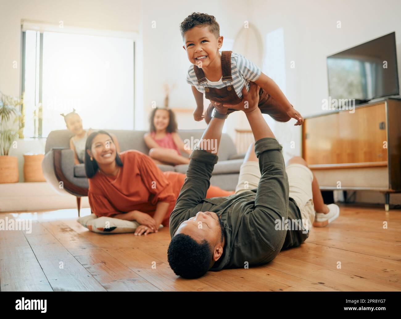 Una famiglia di cinque persone che si rilassa nella sala e si divertono insieme. Adoro la famiglia nera che si unisce al figlio mentre giocano a giochi divertenti sul pavimento a casa Foto Stock