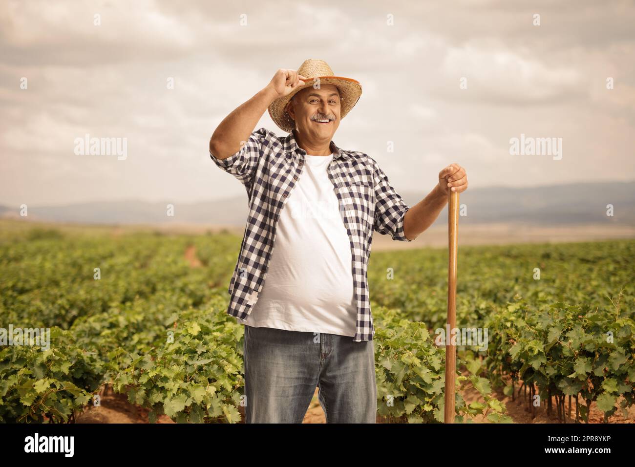 Contadino maturo su un campo di vite saluto con il suo cappello di paglia Foto Stock