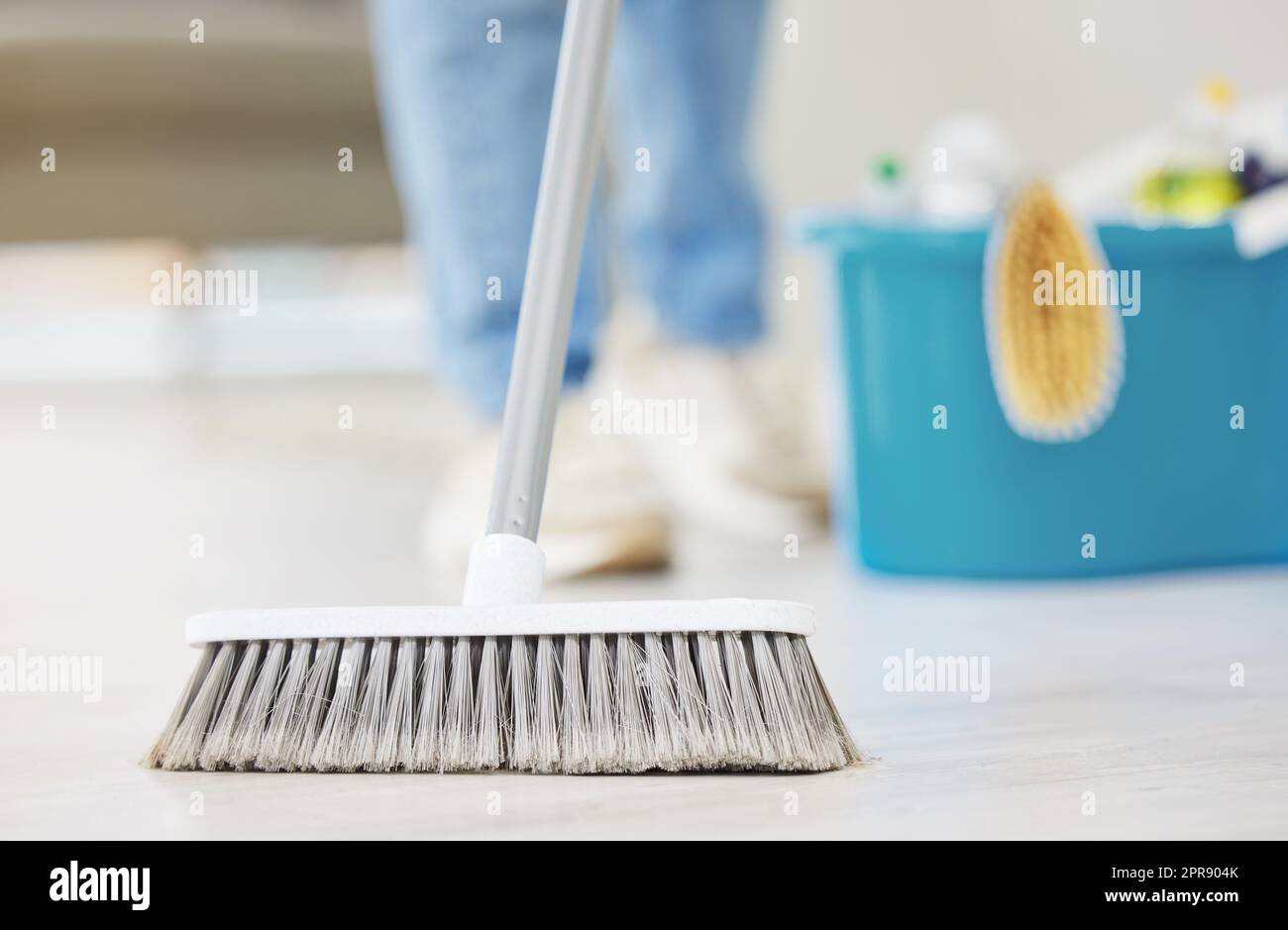 Una donna irriconoscibile che pulisce il pavimento del suo appartamento. Una donna sconosciuta che usa una scopa per pulire il pavimento di polvere Foto Stock