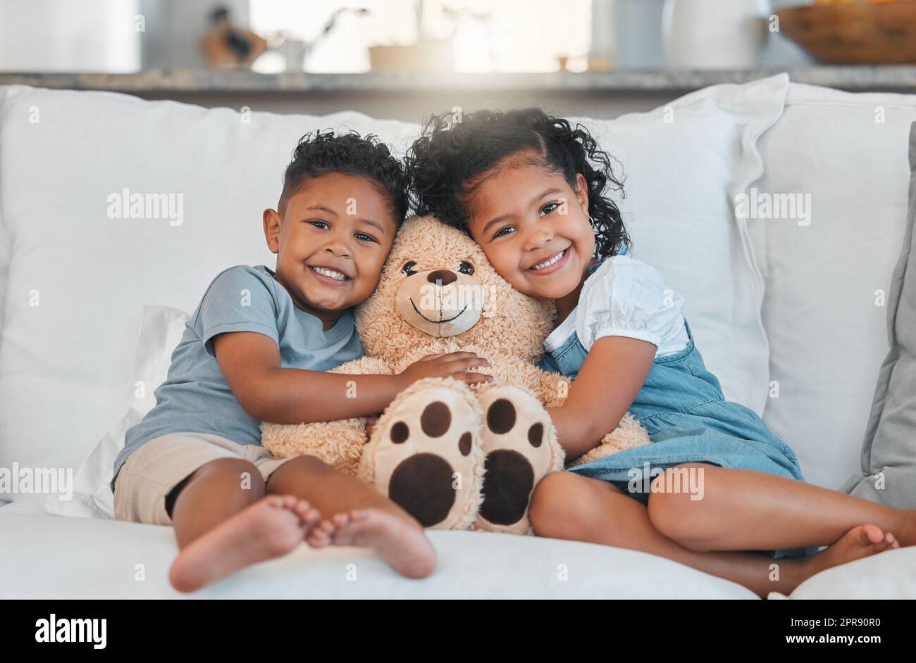 Il nostro Teddy preferito, un fratello e una sorella che trascorrono un po' di tempo insieme sul divano di casa. Foto Stock