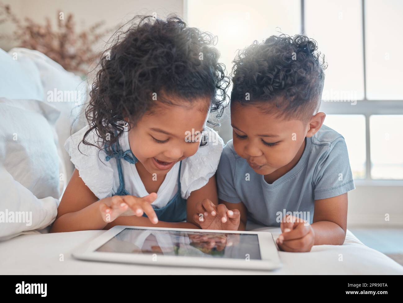 Facciamo giocare un bro di gioco. Un fratello e una sorella utilizzando un tablet digitale insieme a casa. Foto Stock