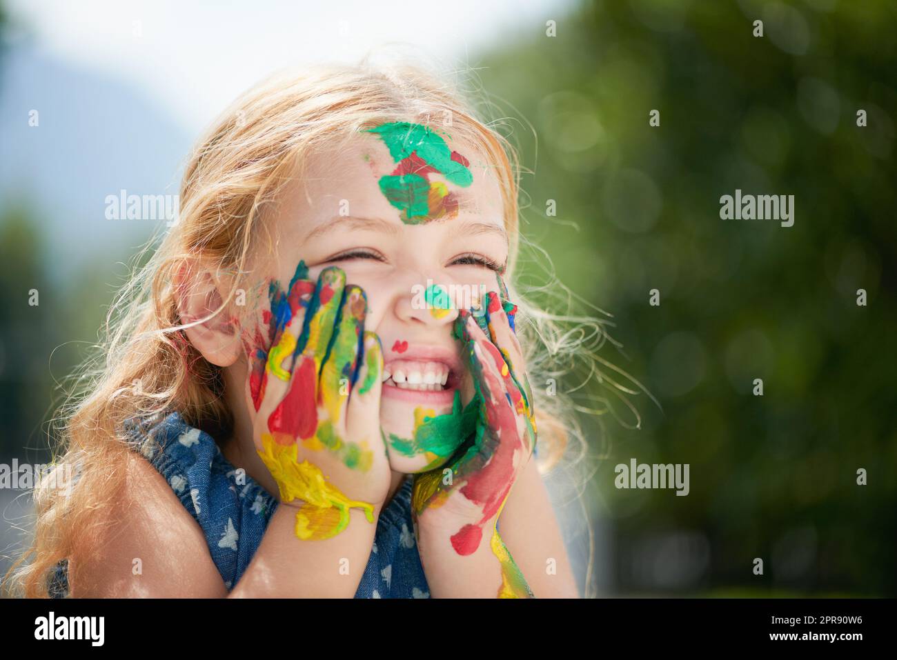 La felicità può essere trovata in una vasca di vernice. Una ragazza piccola felice coperta di vernice. Foto Stock