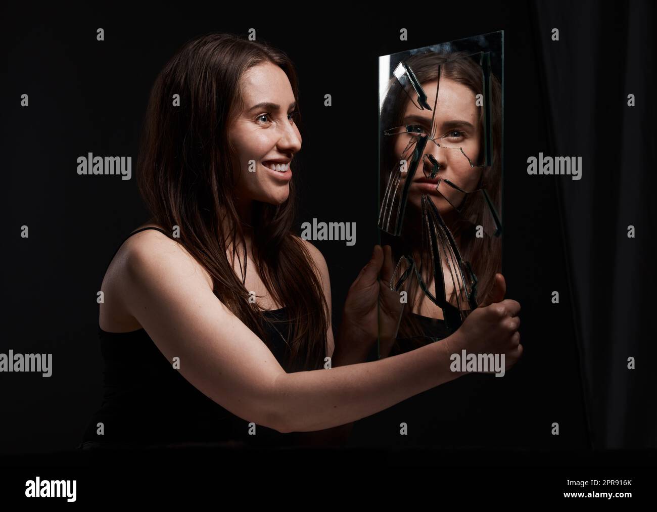 Non mi conoscete, una donna creepy che grinning alla sua riflessione in uno specchio rotto. Foto Stock