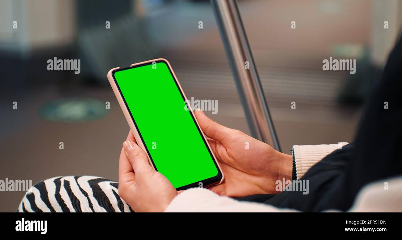 Le mani di una donna da vicino guardano al telefono sul tasto croma dello schermo verde sul treno. Foto Stock