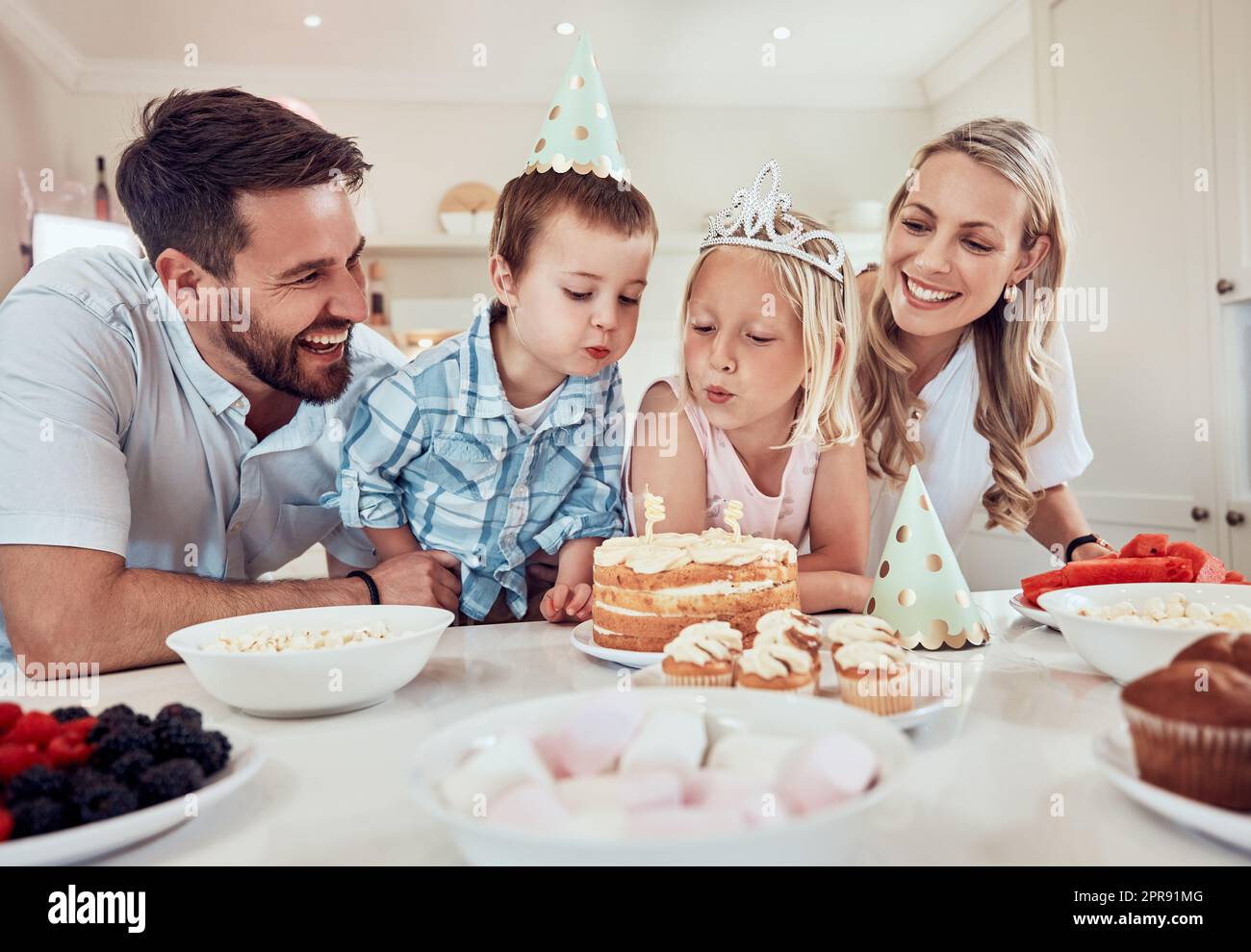 Buona famiglia che festeggia il compleanno delle figlie. Bambina che fa saltare le candele sulla sua torta di compleanno. Fratello e sorella festeggiano il loro compleanno con una festa. Famiglia caucasica alla festa di compleanno Foto Stock