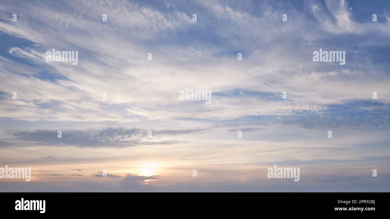 Copia lo spazio con le nuvole in una giornata di sole con un cielo blu. Atmosfera tranquilla e carta da parati con paesaggio nuvoloso e sole nella natura. Splendido scenario di paradiso con il tramonto nuvoloso all'esterno Foto Stock