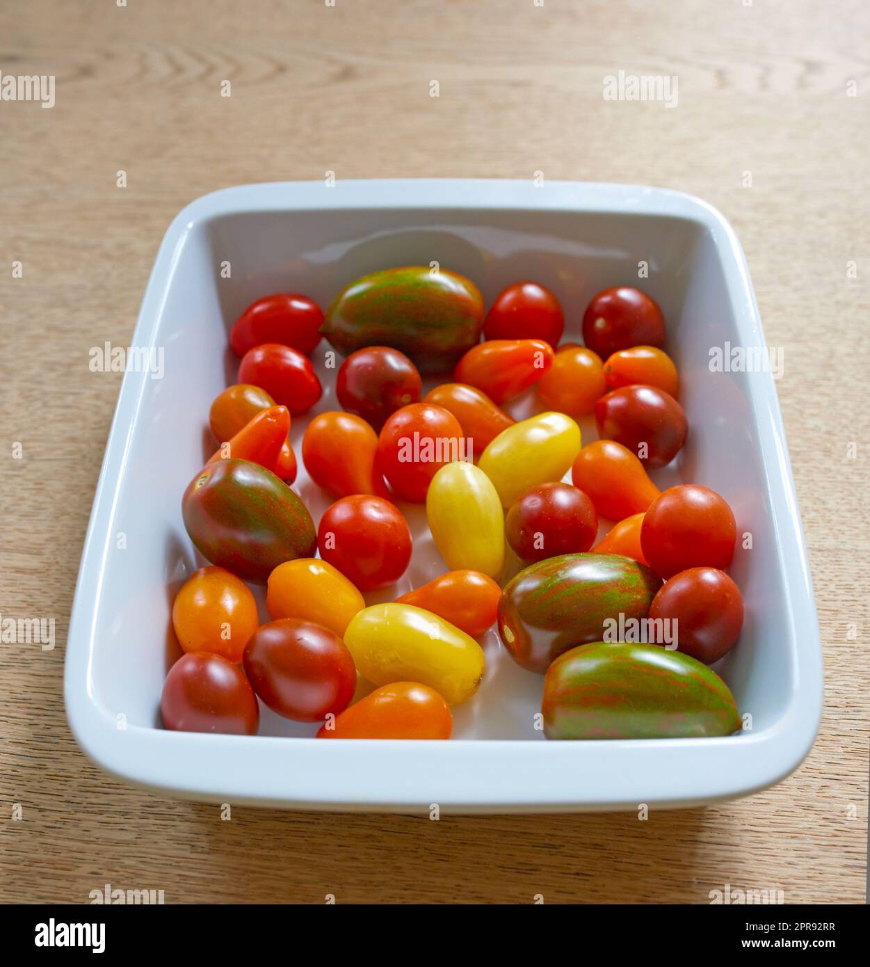 Primo piano dei pomodori ciliegini pronti da cuocere in una cucina con pomodoro rosso, giallo e verde succoso in una ciotola in un ristorante. Un superfood che verrà aggiunto a un pasto sano e nutriente per la salute Foto Stock