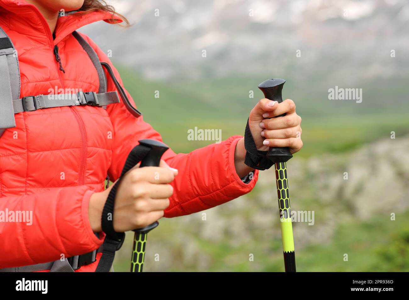 L'escursionista passa le mani in rosso usando i pali per camminare nella montagna Foto Stock